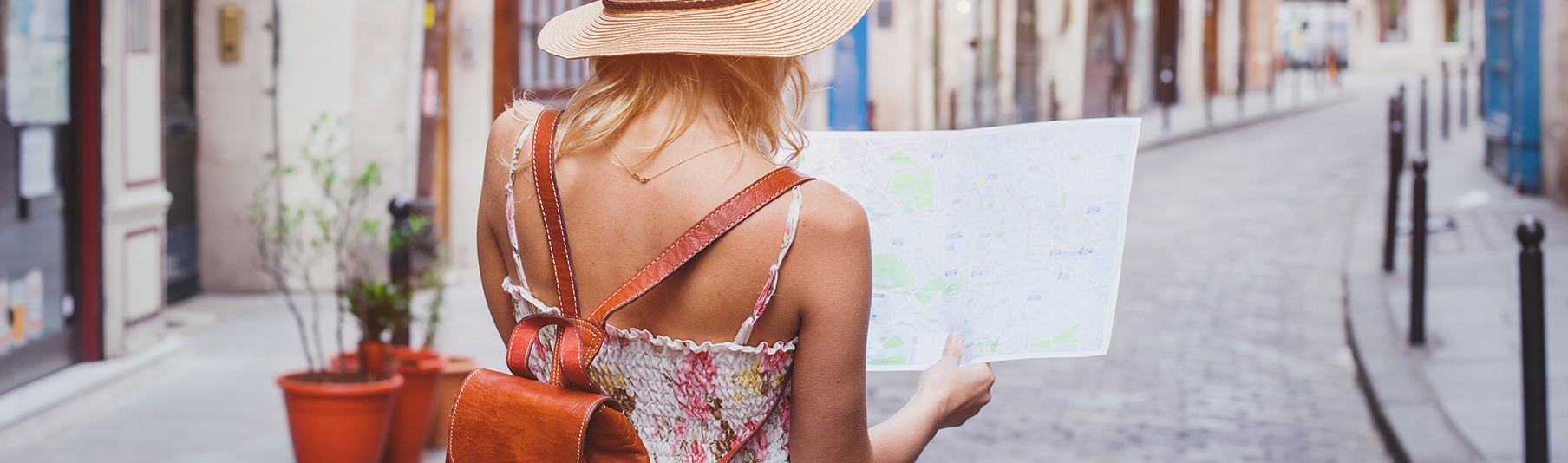 Travel Insurance: A woman on holiday looking at a map while walking the streets